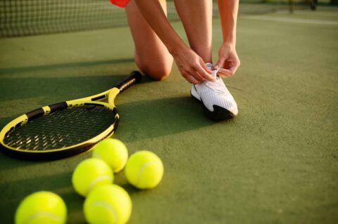 female-tennis-player-ties-her-shoelaces-PW9GWML